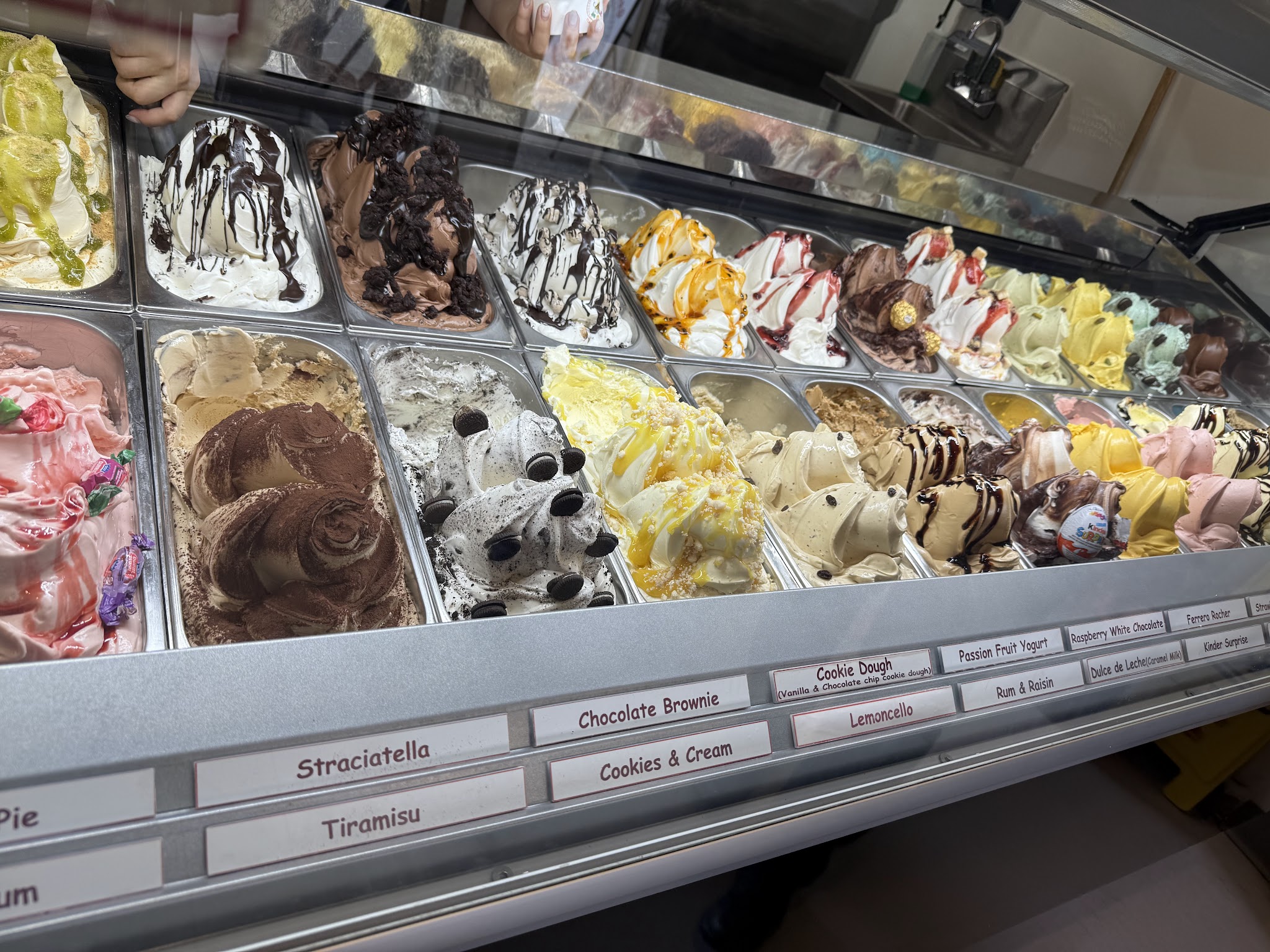 Close-up of gelato display with labeled flavors including Stracciatella, Tiramisu, and Chocolate Brownie
