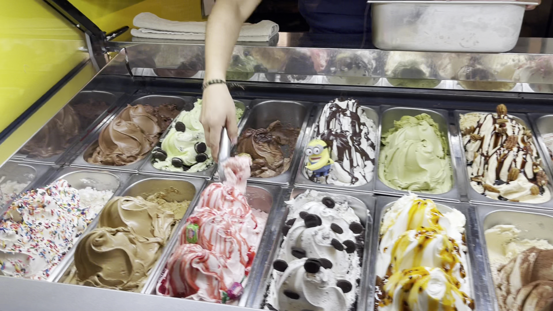Staff member scooping gelato from the colorful display case